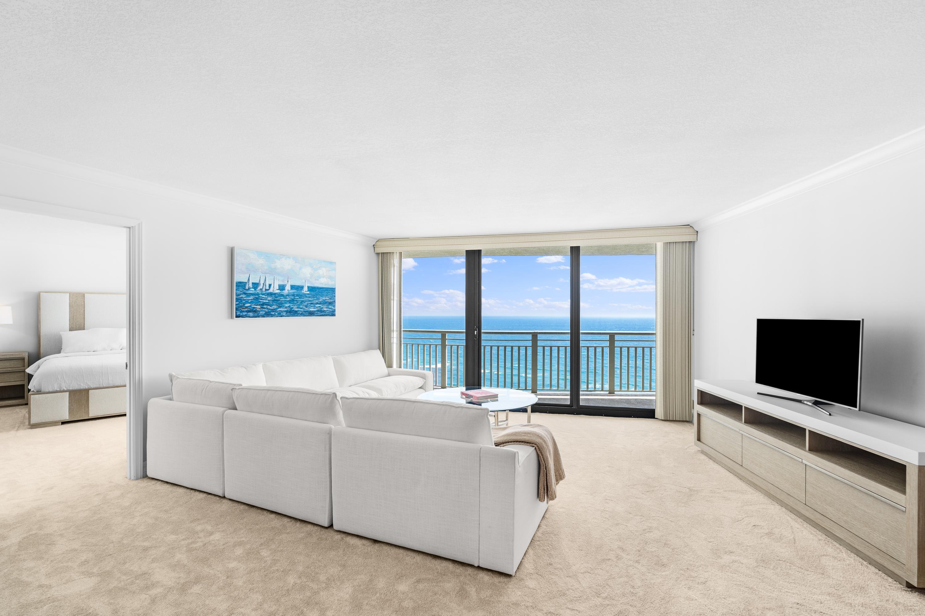 a living room with furniture a flat screen tv and a floor to ceiling window