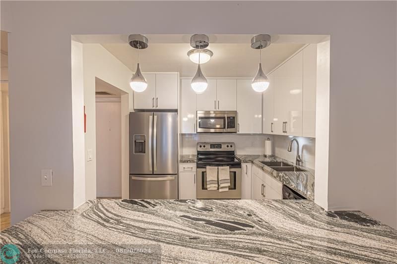 a kitchen with stainless steel appliances kitchen island granite countertop a refrigerator and a stove top oven