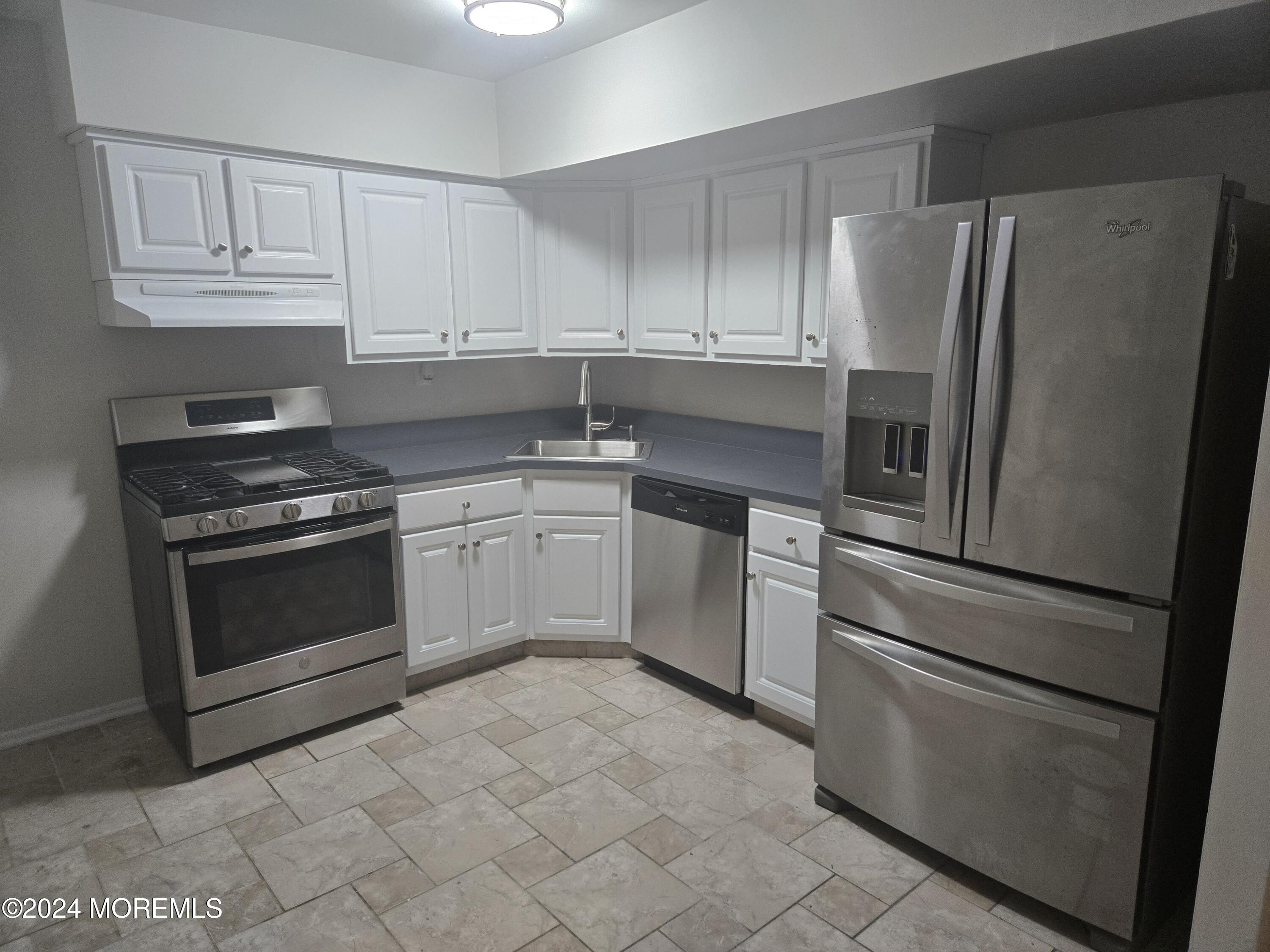 a kitchen with cabinets stainless steel appliances and a counter space