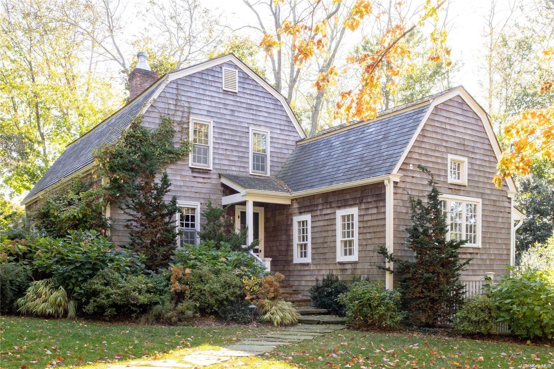 a view of a house with brick walls plants and large tree