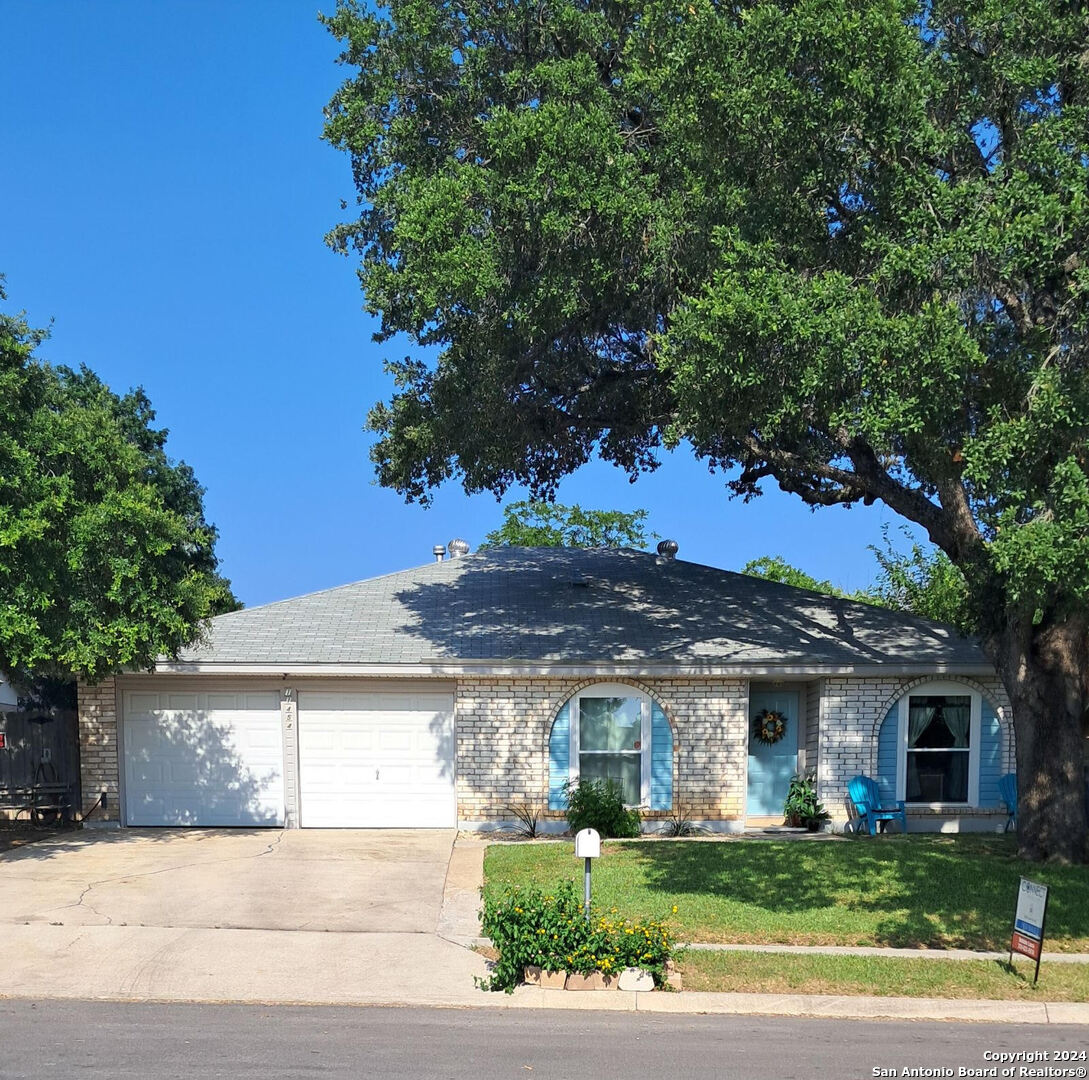 a view of a white house next to a yard with potted plants