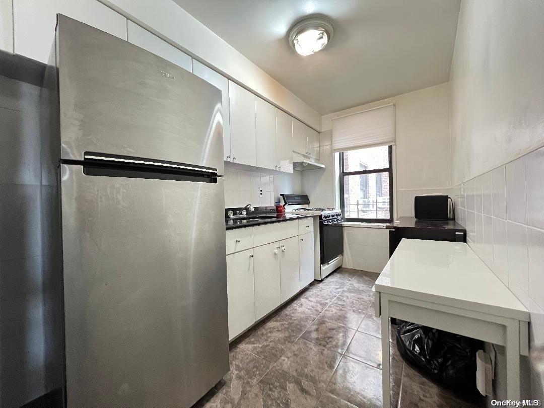 a kitchen with a refrigerator and white cabinets