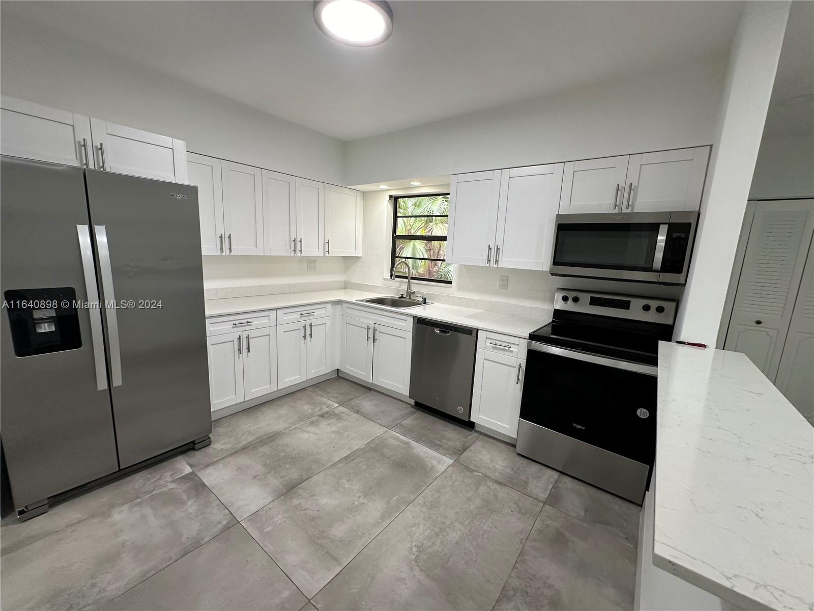 a kitchen with granite countertop a refrigerator stove top oven and sink