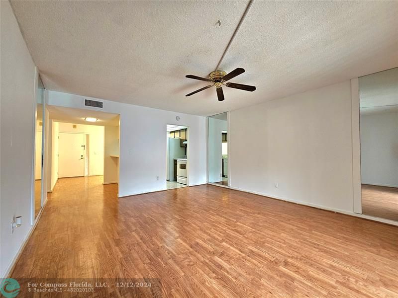 a view of an empty room with window and wooden floor