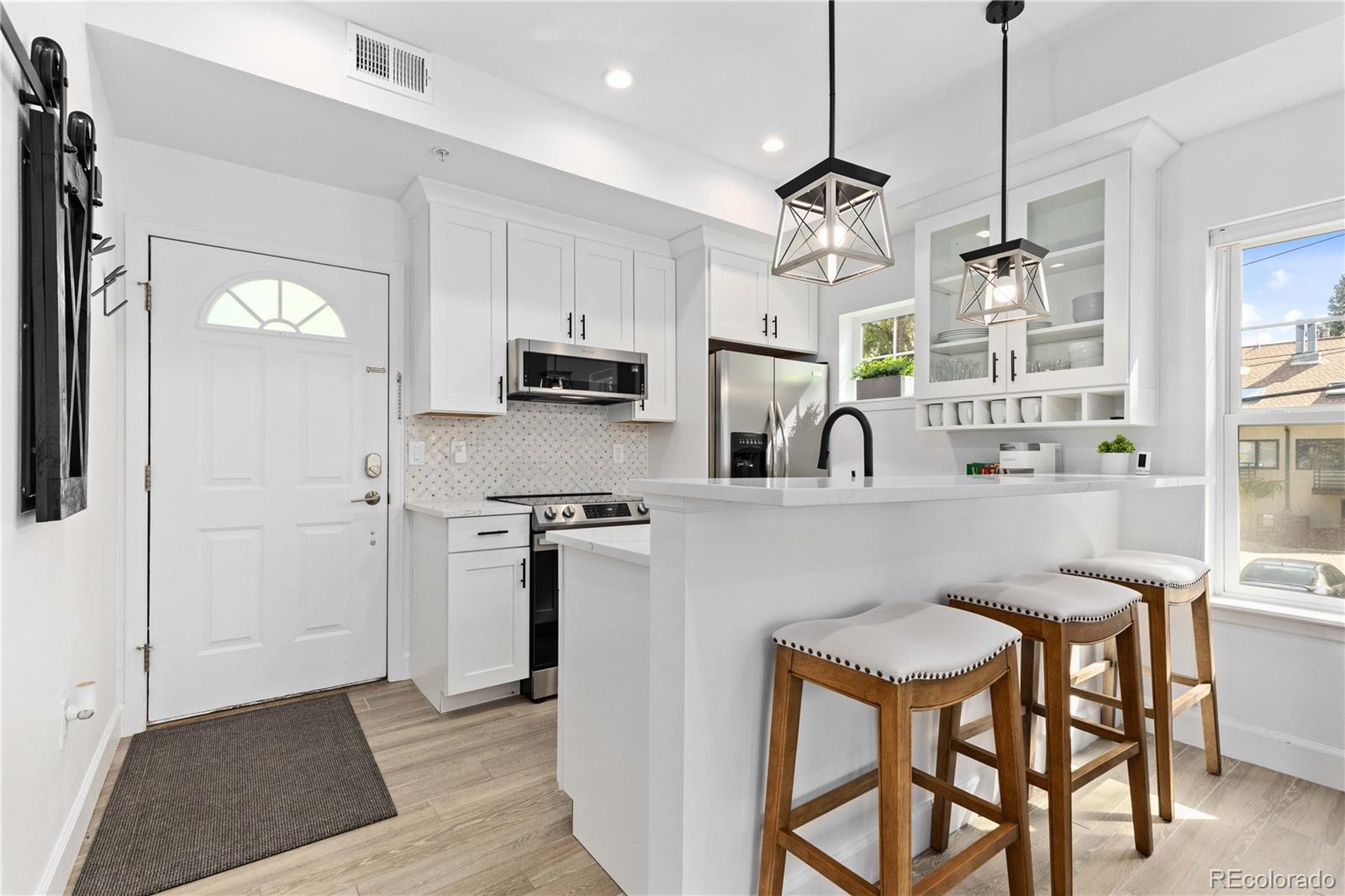 a kitchen with stainless steel appliances granite countertop a stove a sink a refrigerator a microwave a dining table and chairs with wooden floor