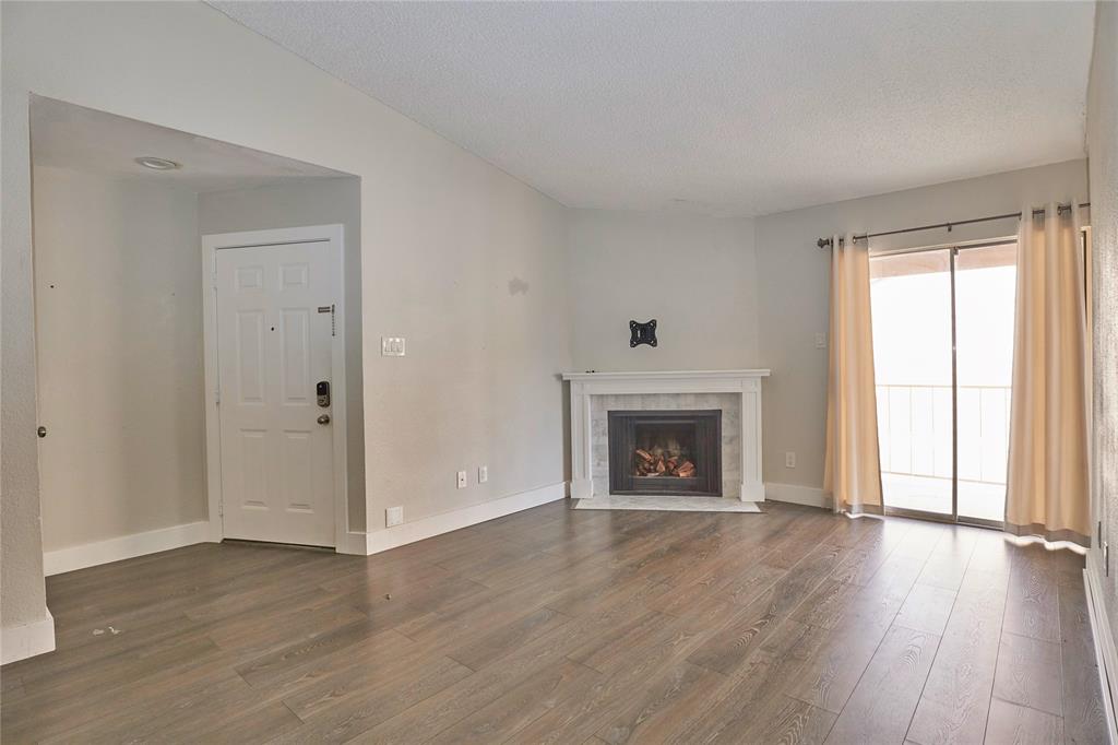 an empty room with wooden floor fireplace and windows