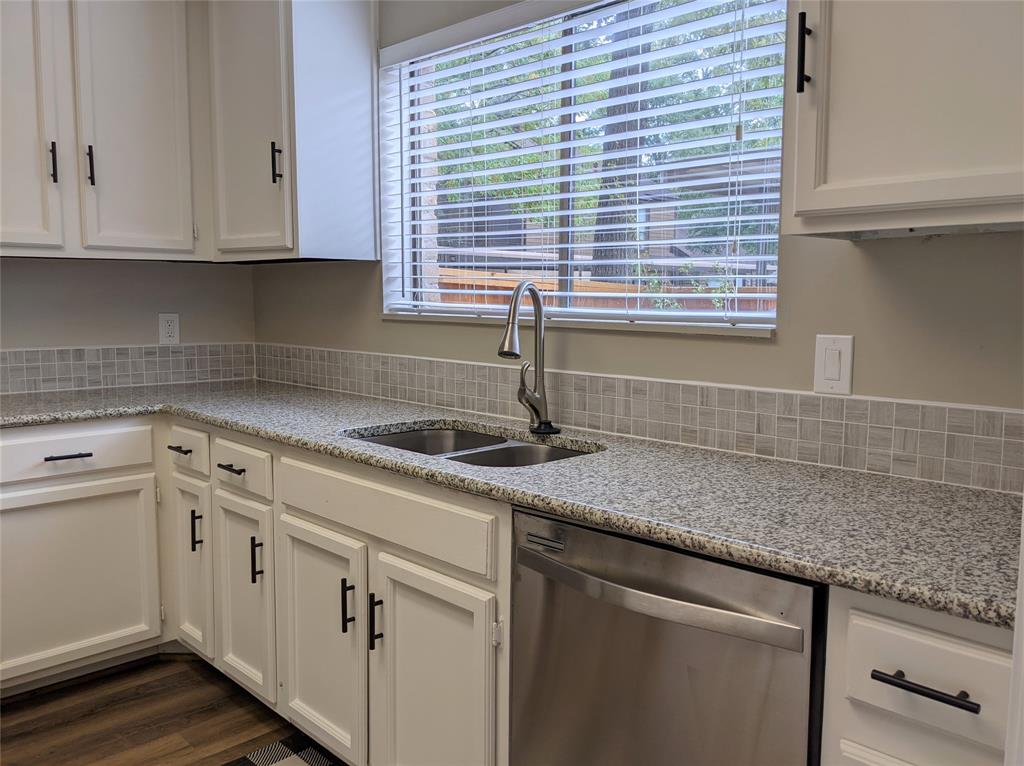 a kitchen with stainless steel appliances granite countertop white cabinets and a window