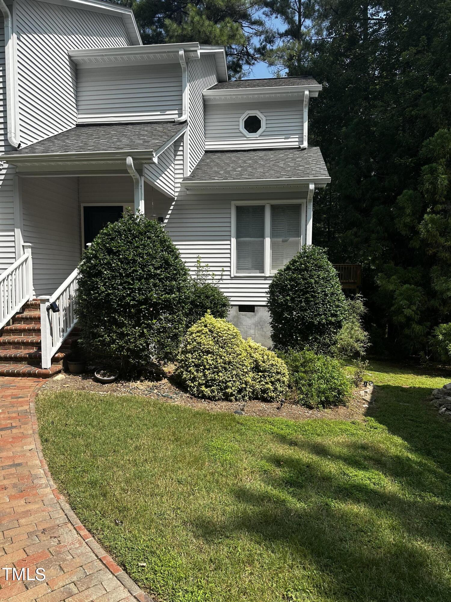 a view of a white house with a yard and potted plants