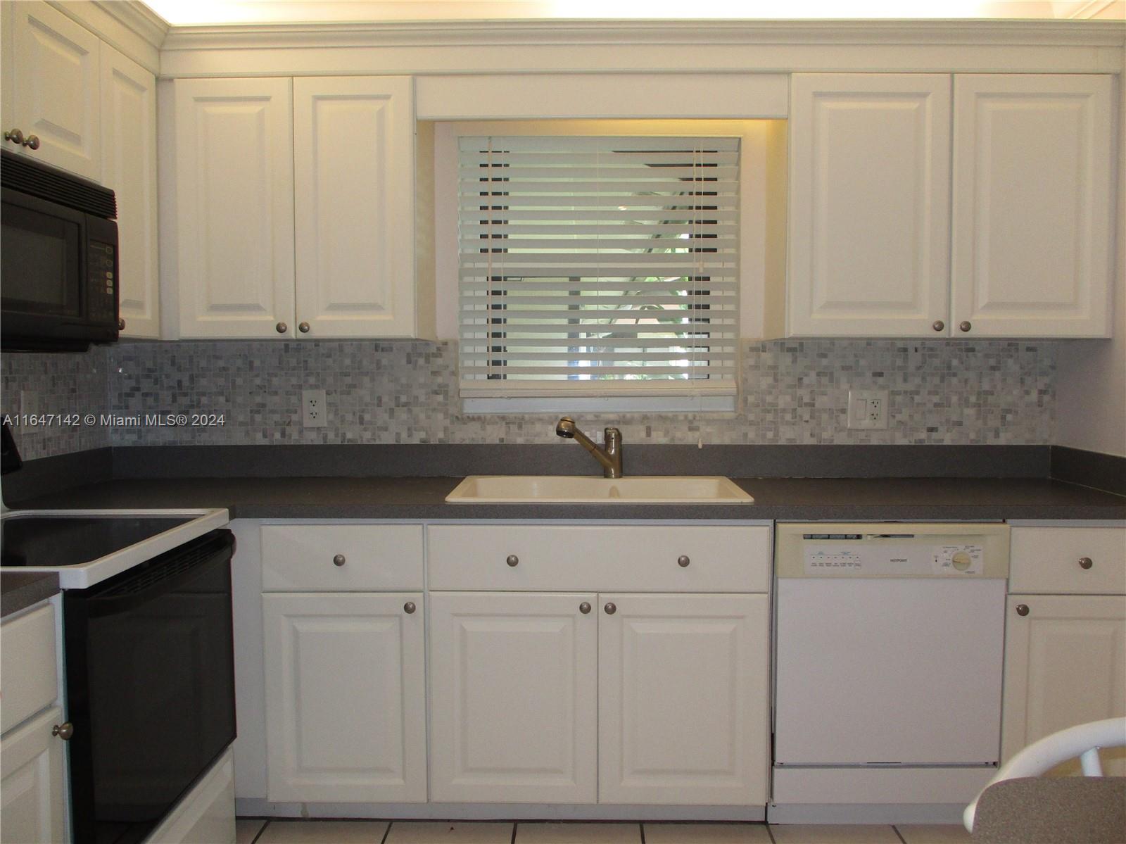 a kitchen with granite countertop white cabinets and a sink