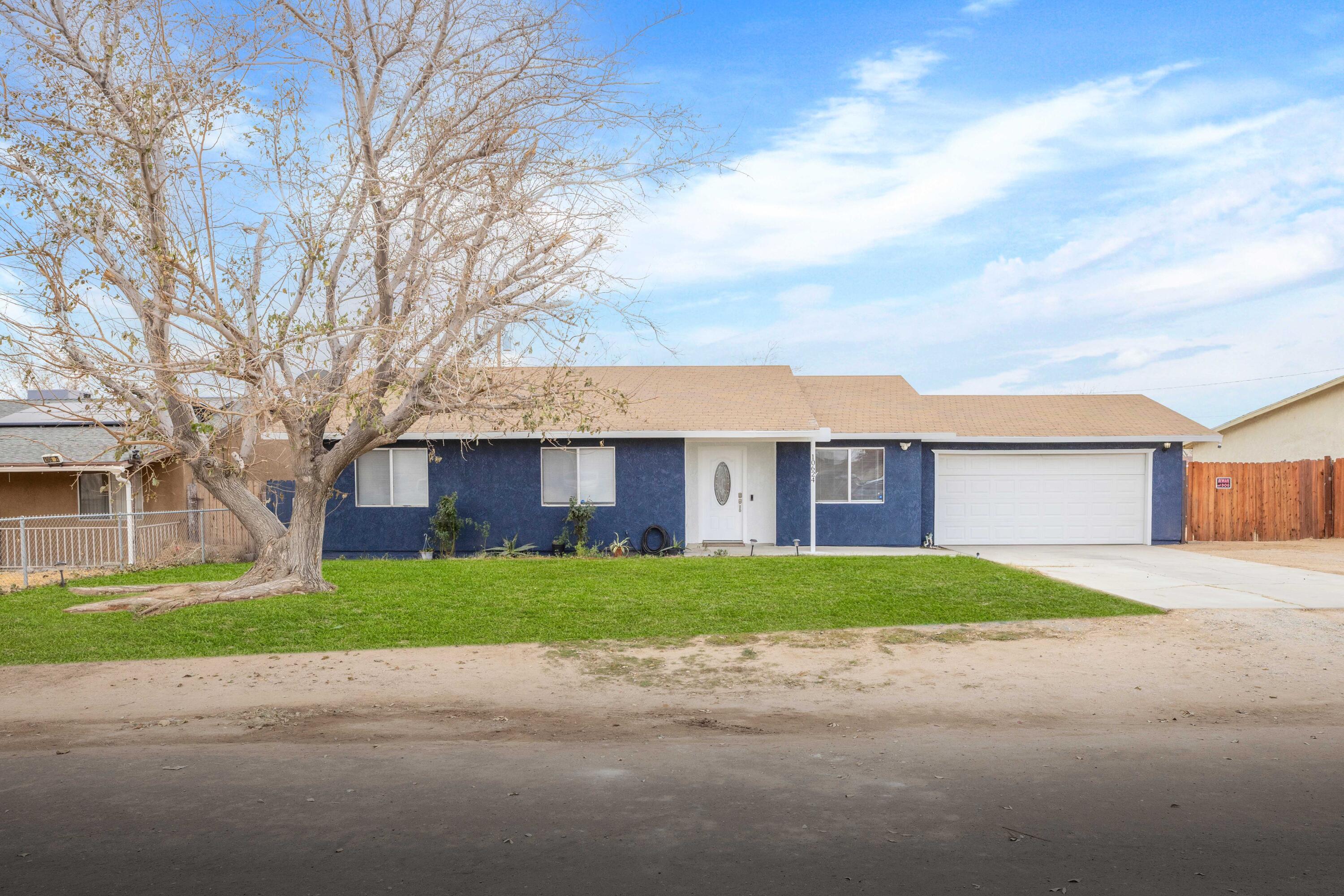 a view of a house next to a yard with large tree