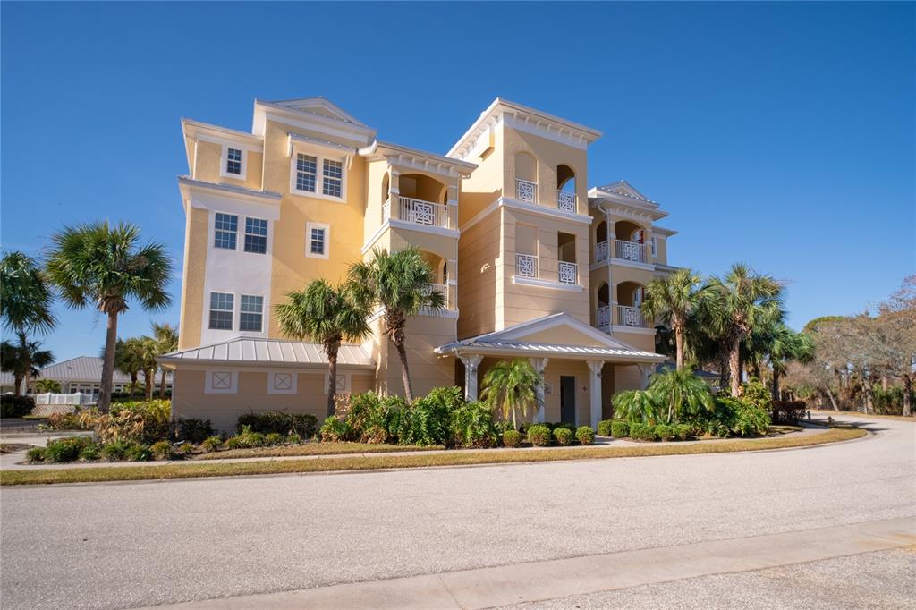 a front view of a multi story residential apartment building with yard and parking space