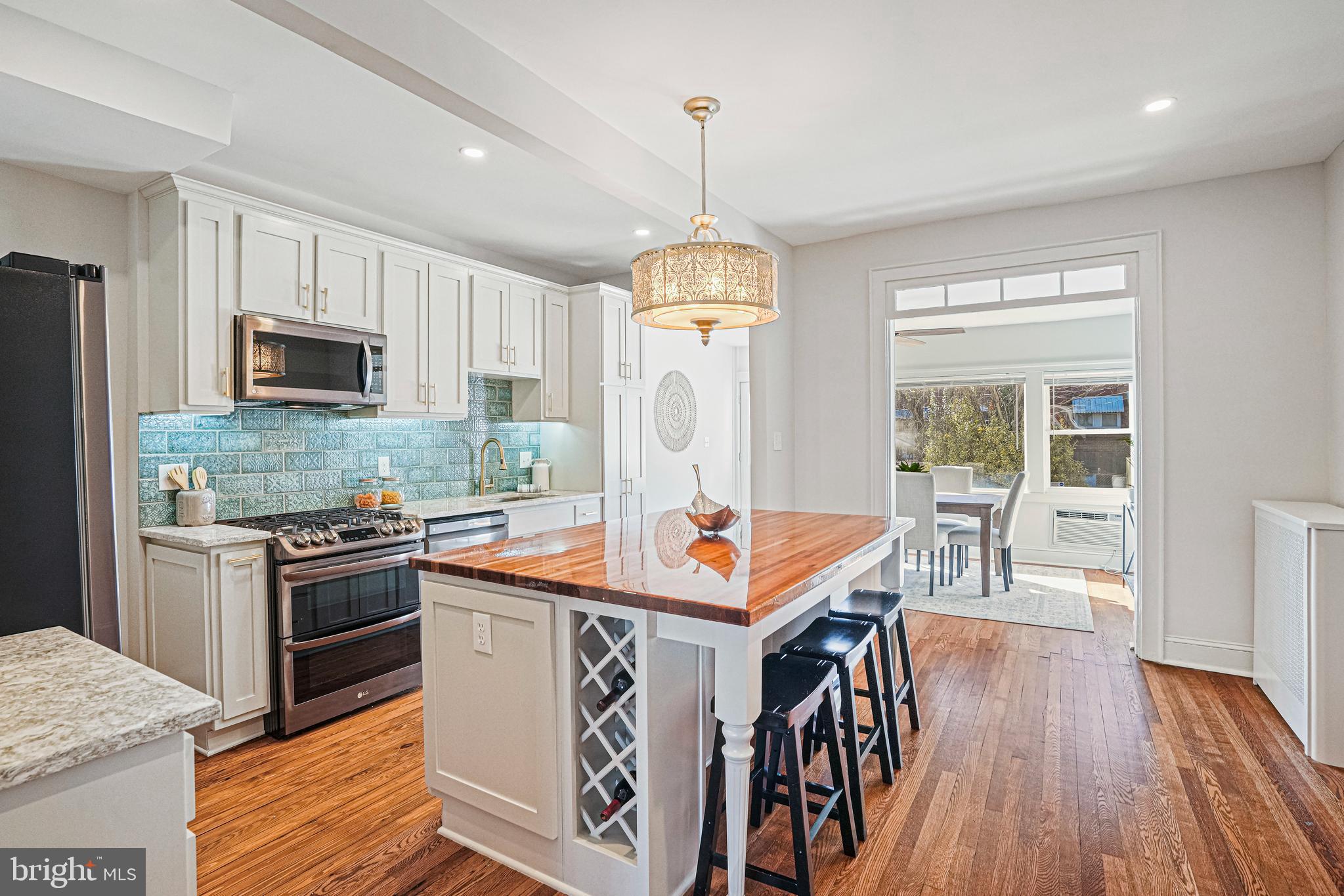 a kitchen with stainless steel appliances granite countertop a stove top oven a sink dishwasher a refrigerator and a dining table with wooden floor