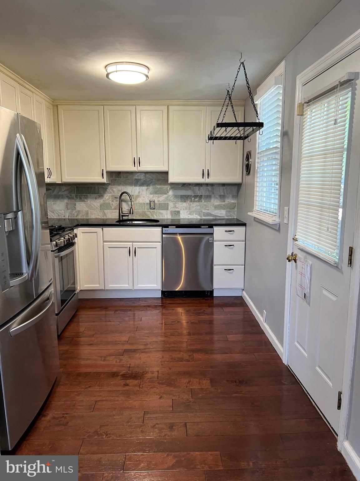 a kitchen with granite countertop a refrigerator and a stove top oven