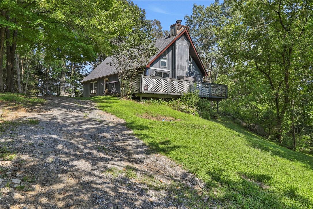 View of property exterior featuring a wooden deck and a lawn