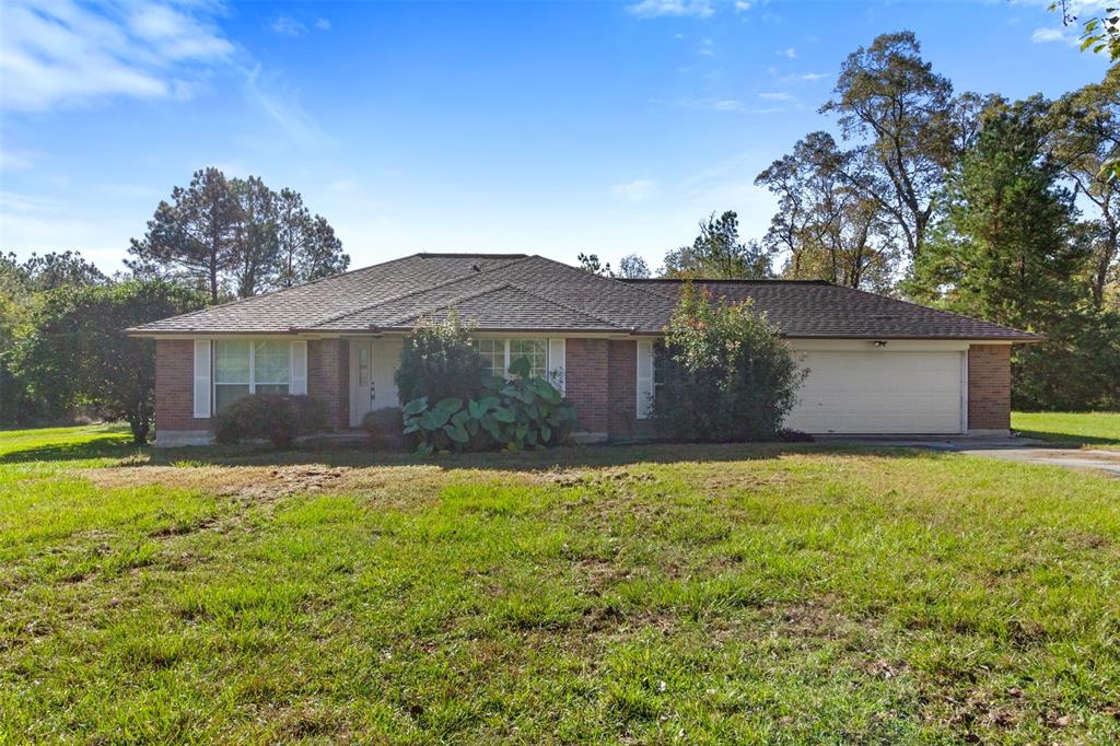 a front view of house with yard and trees in the background