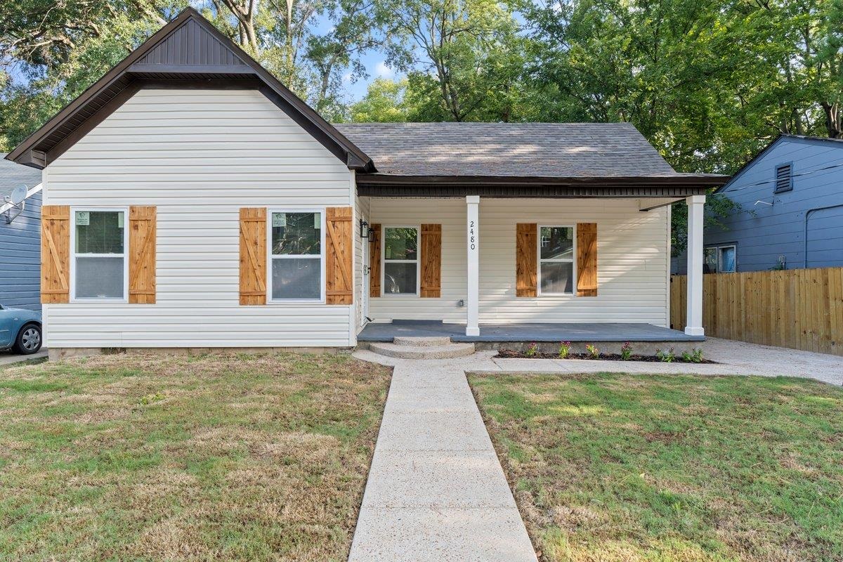 View of front of home featuring covered porch and a front lawn