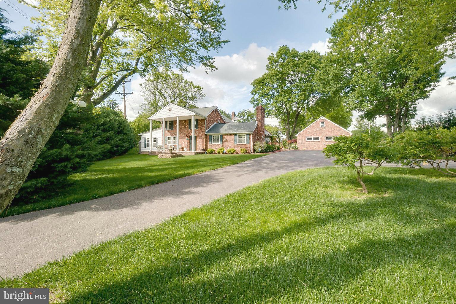 a view of a house with a big yard plants and large trees