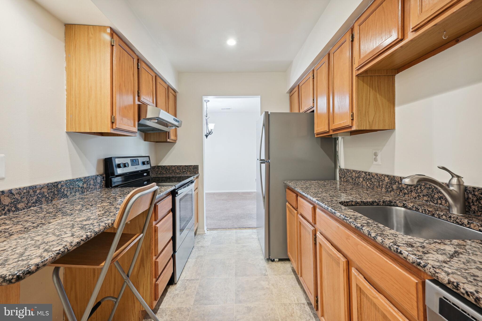 a kitchen with granite countertop a sink a stove and cabinets