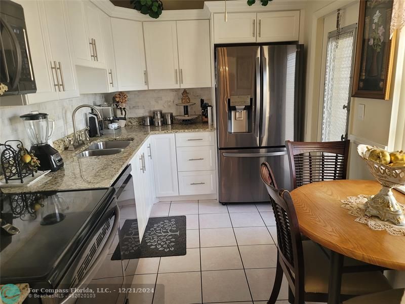 a kitchen with stainless steel appliances granite countertop a sink refrigerator and cabinets