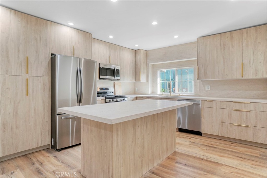 a kitchen with stainless steel appliances a sink a stove a refrigerator and cabinets