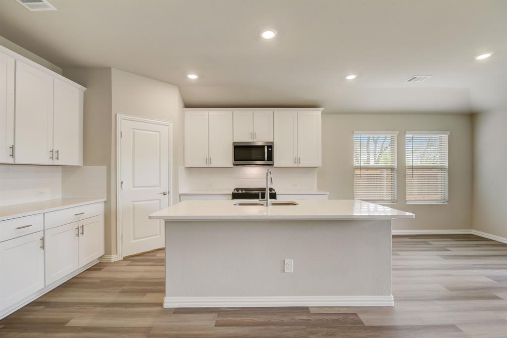 a kitchen with stainless steel appliances granite countertop a sink a stove a refrigerator and white cabinets