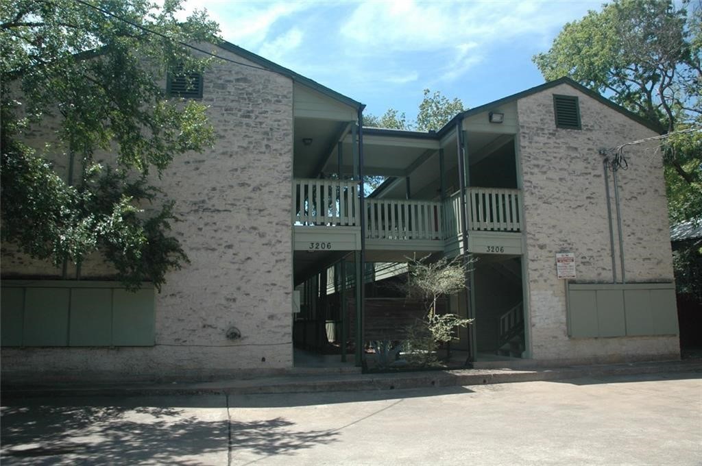 a view of a brick house with large windows and a small yard