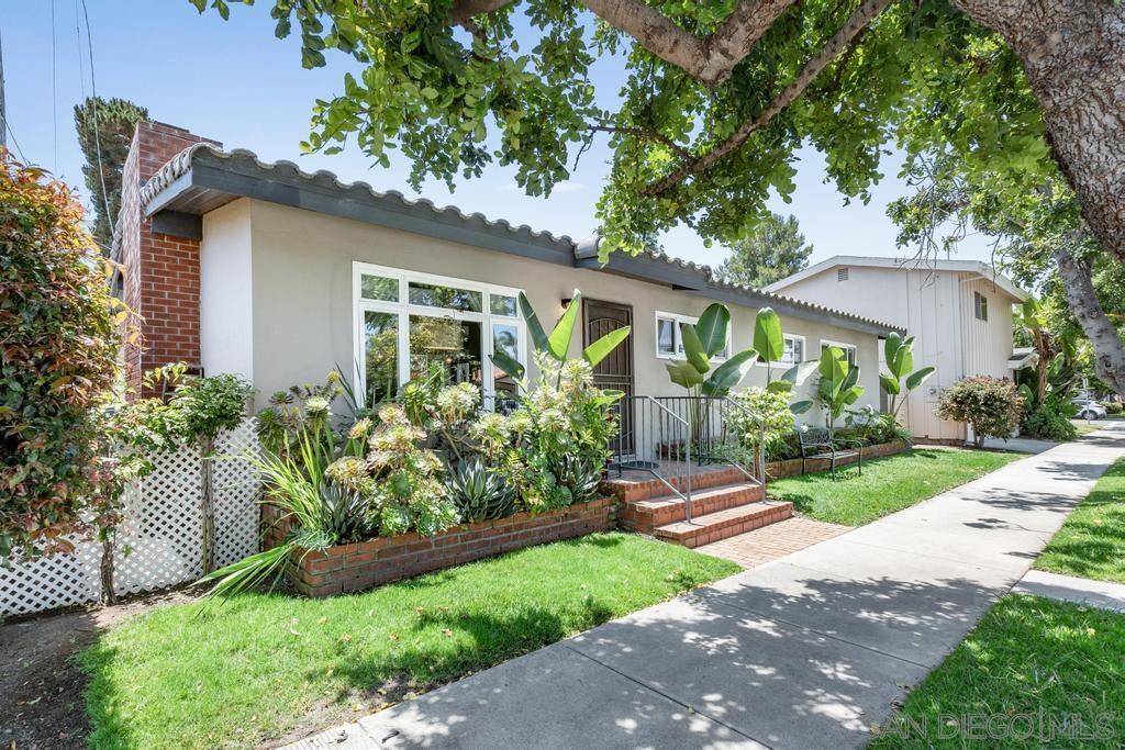 a front view of a house with a yard and potted plants