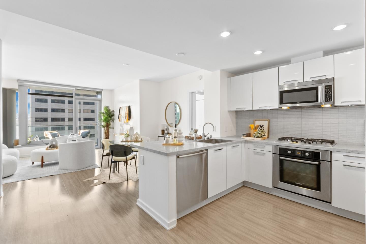 a kitchen with stainless steel appliances granite countertop a stove top oven a sink dishwasher a microwave oven and a dining table with wooden floor