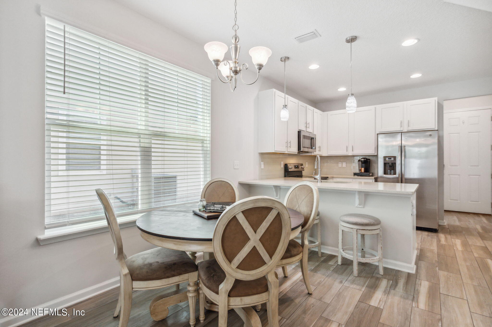 a kitchen with stainless steel appliances kitchen island granite countertop a dining table chairs and white cabinets