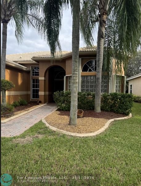 a view of a house with small yard plants and palm trees