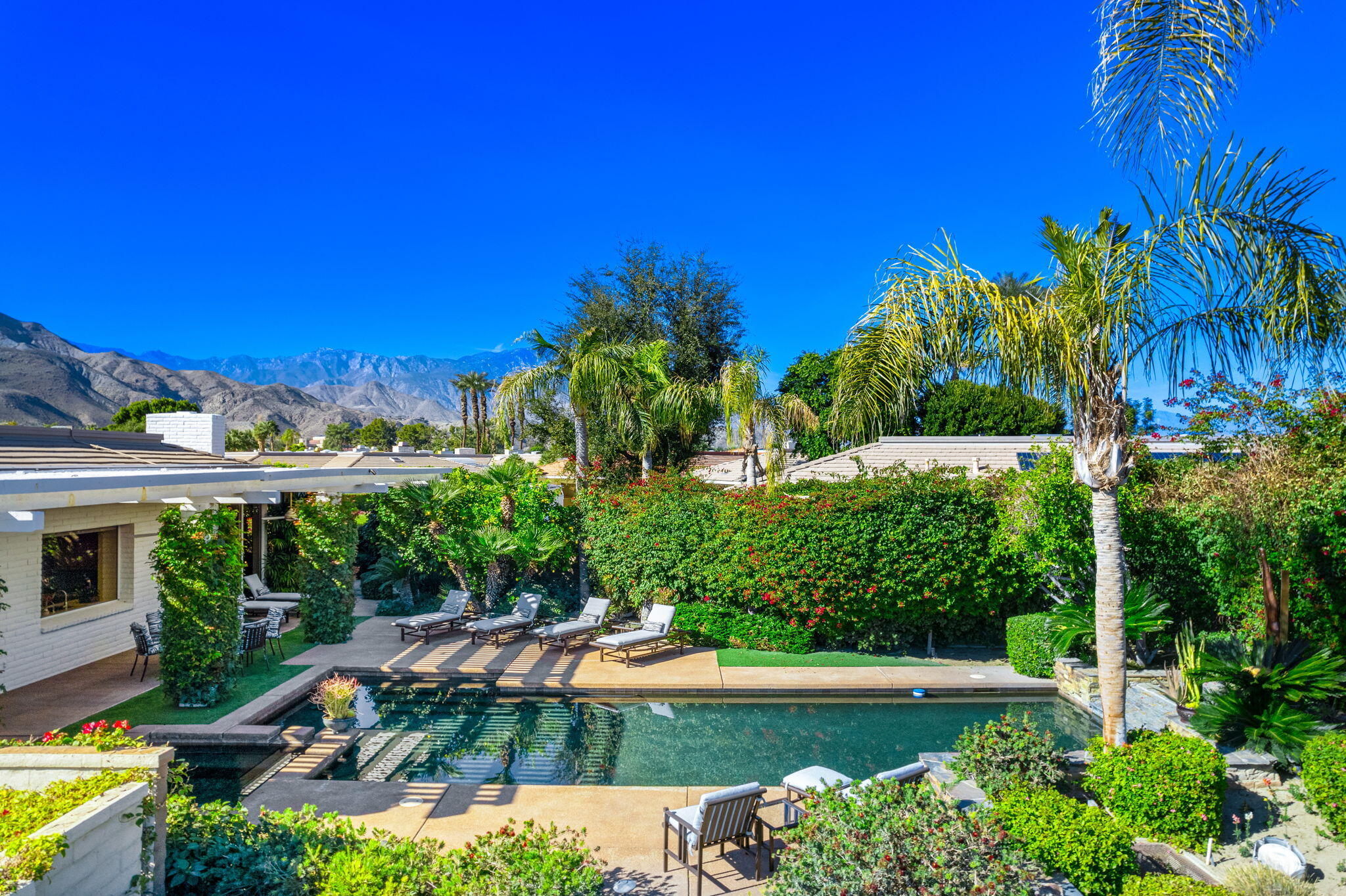 a view of a swimming pool with lawn chairs under an umbrella