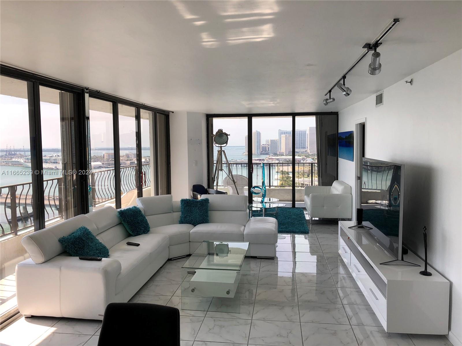 a living room with furniture large windows and flat screen tv