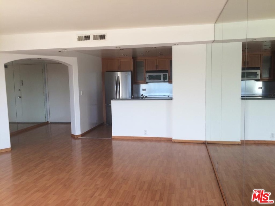 a view of a kitchen with fridge and wooden floor