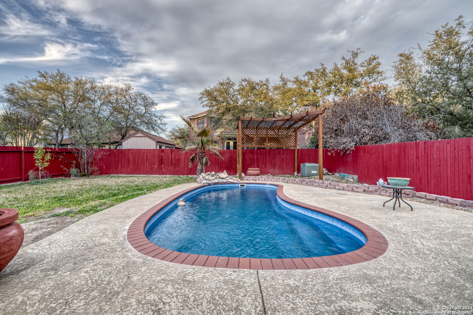 a view of a swimming pool with red chairs in front of a yard