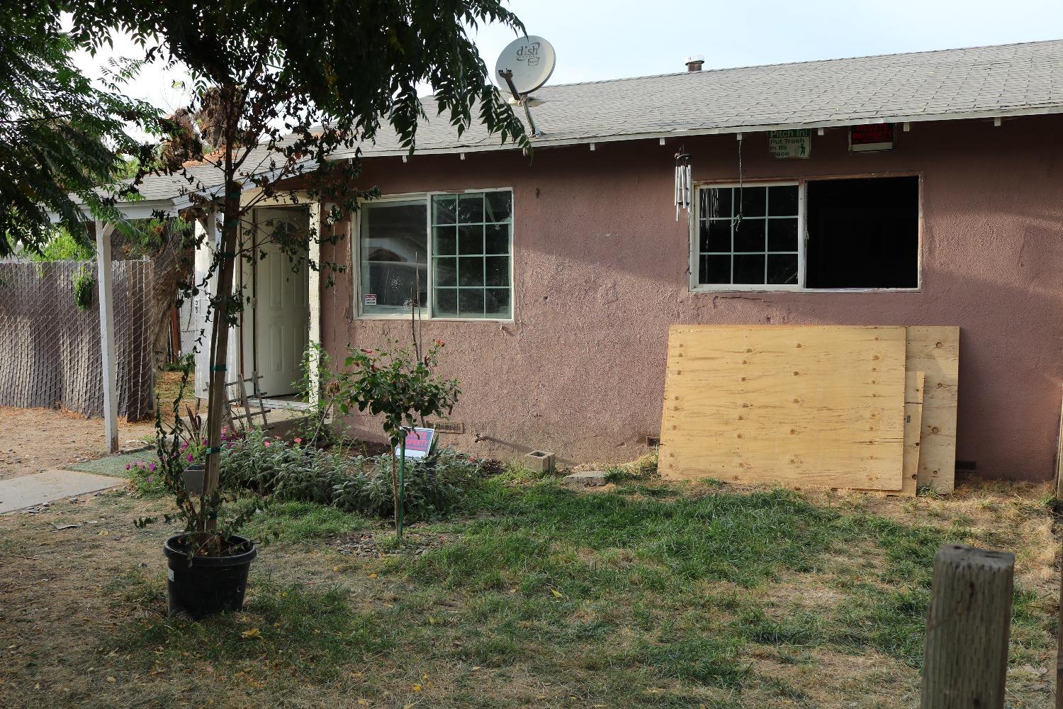 a backyard of a house with potted plants and large tree