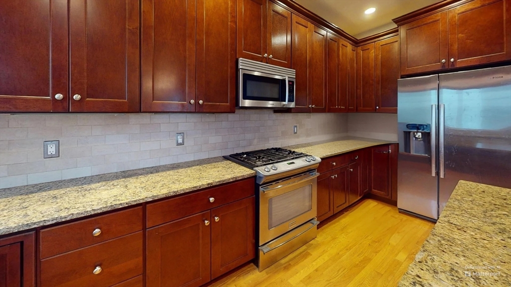 a kitchen with granite countertop wooden cabinets stainless steel appliances and a counter space