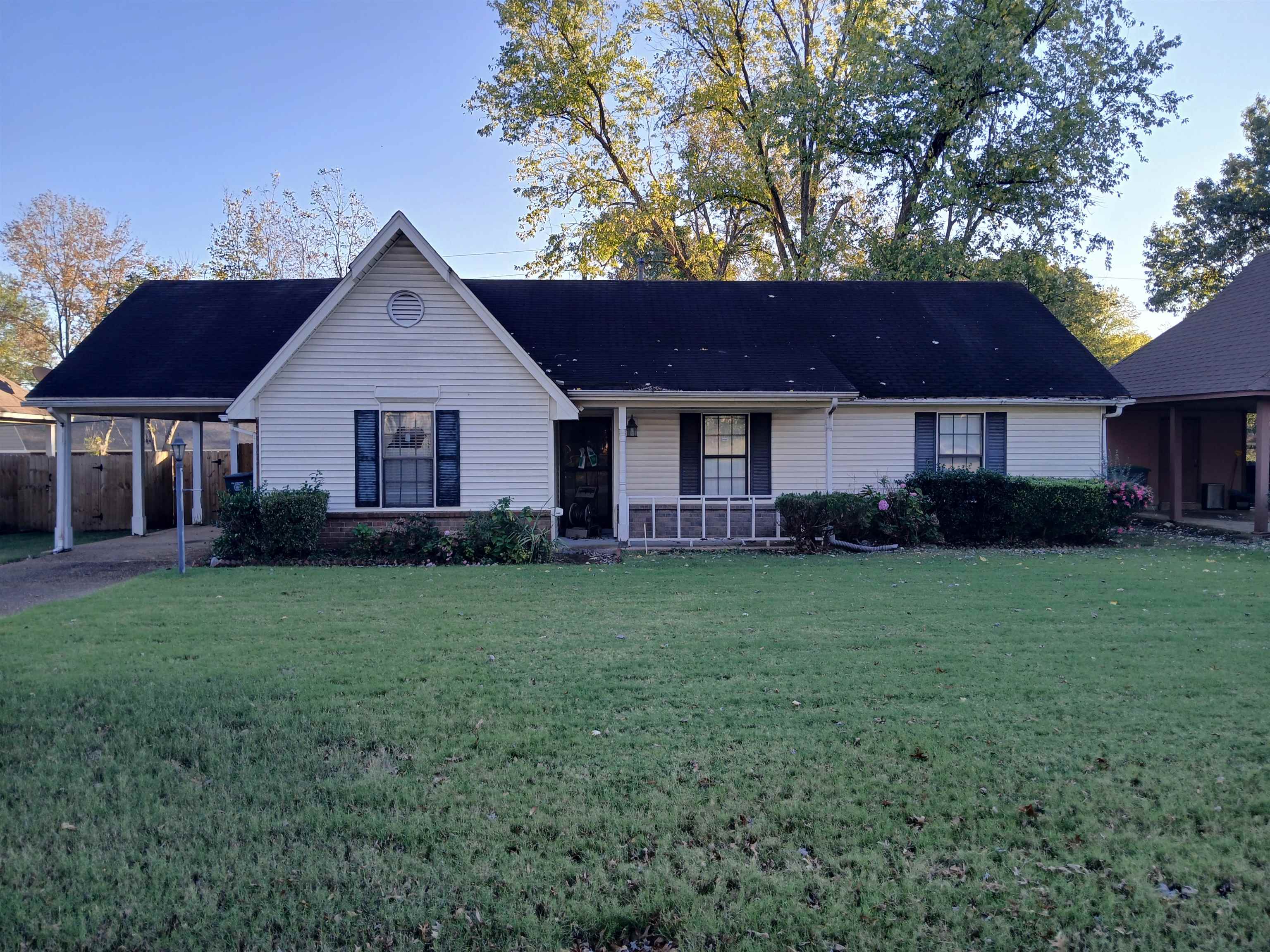 Ranch-style house with a porch, a front yard, and a carport