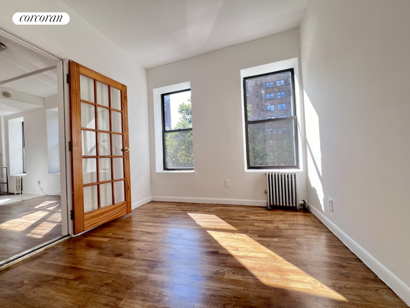 an empty room with wooden floor and windows