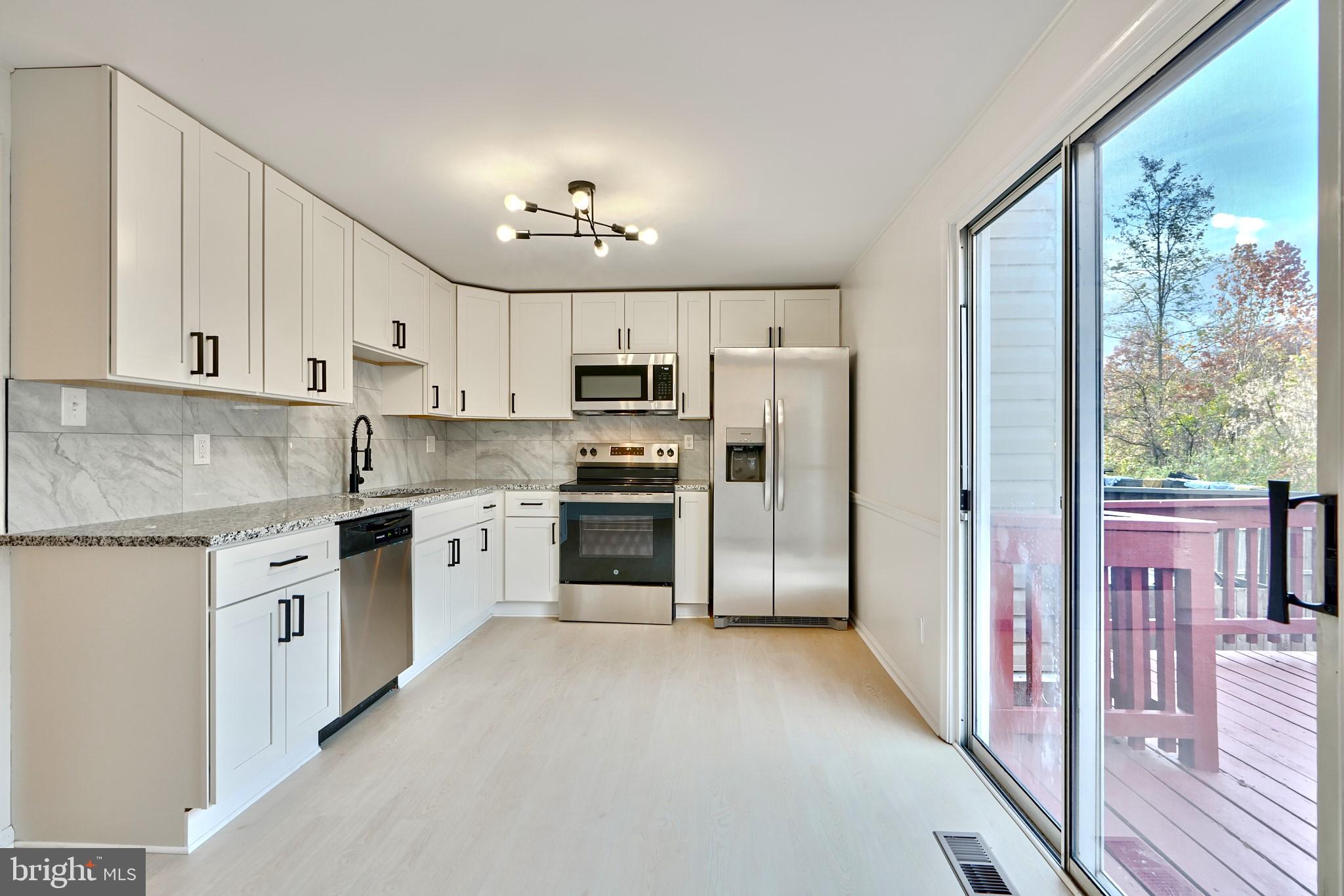 a kitchen with granite countertop a refrigerator stove top oven and sink