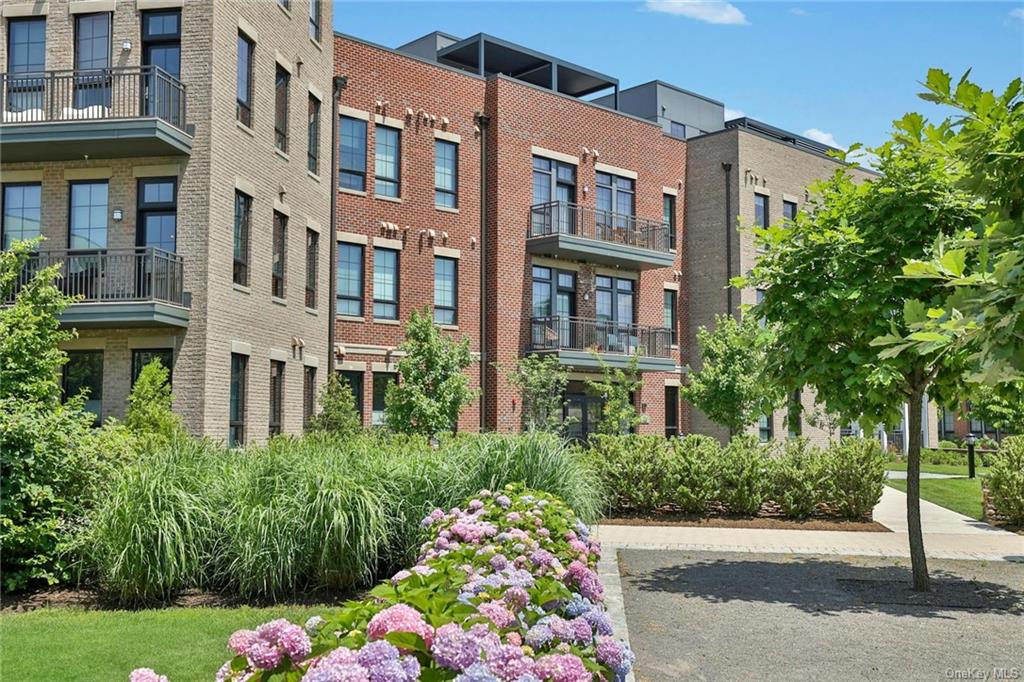 a front view of a multi story residential apartment building with yard and bench