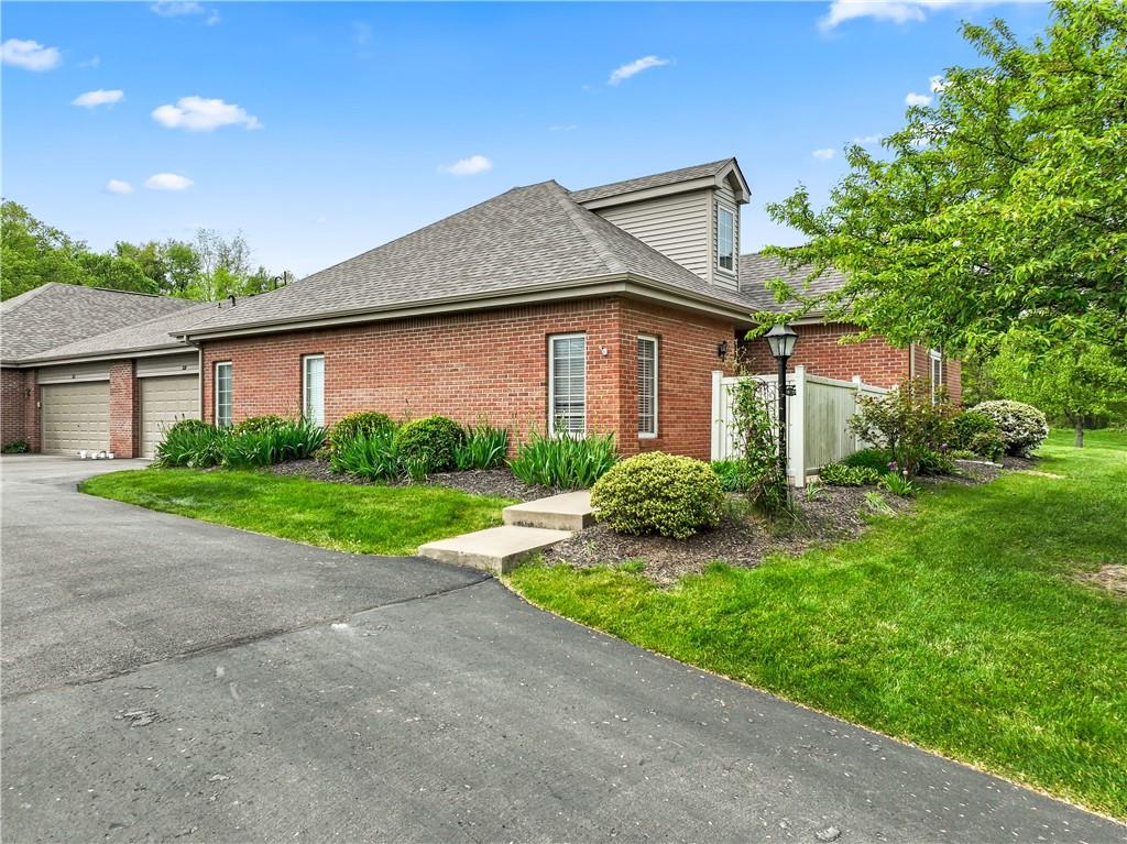 a view of a house with a big yard plants and large tree