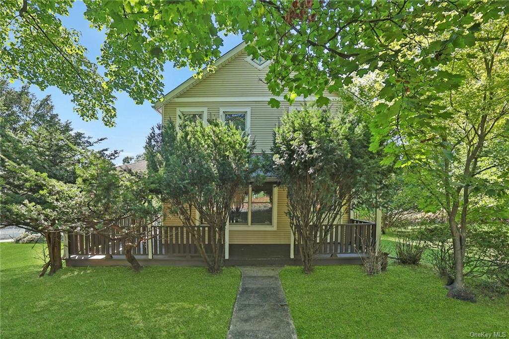 a view of a house next to a big yard and large trees