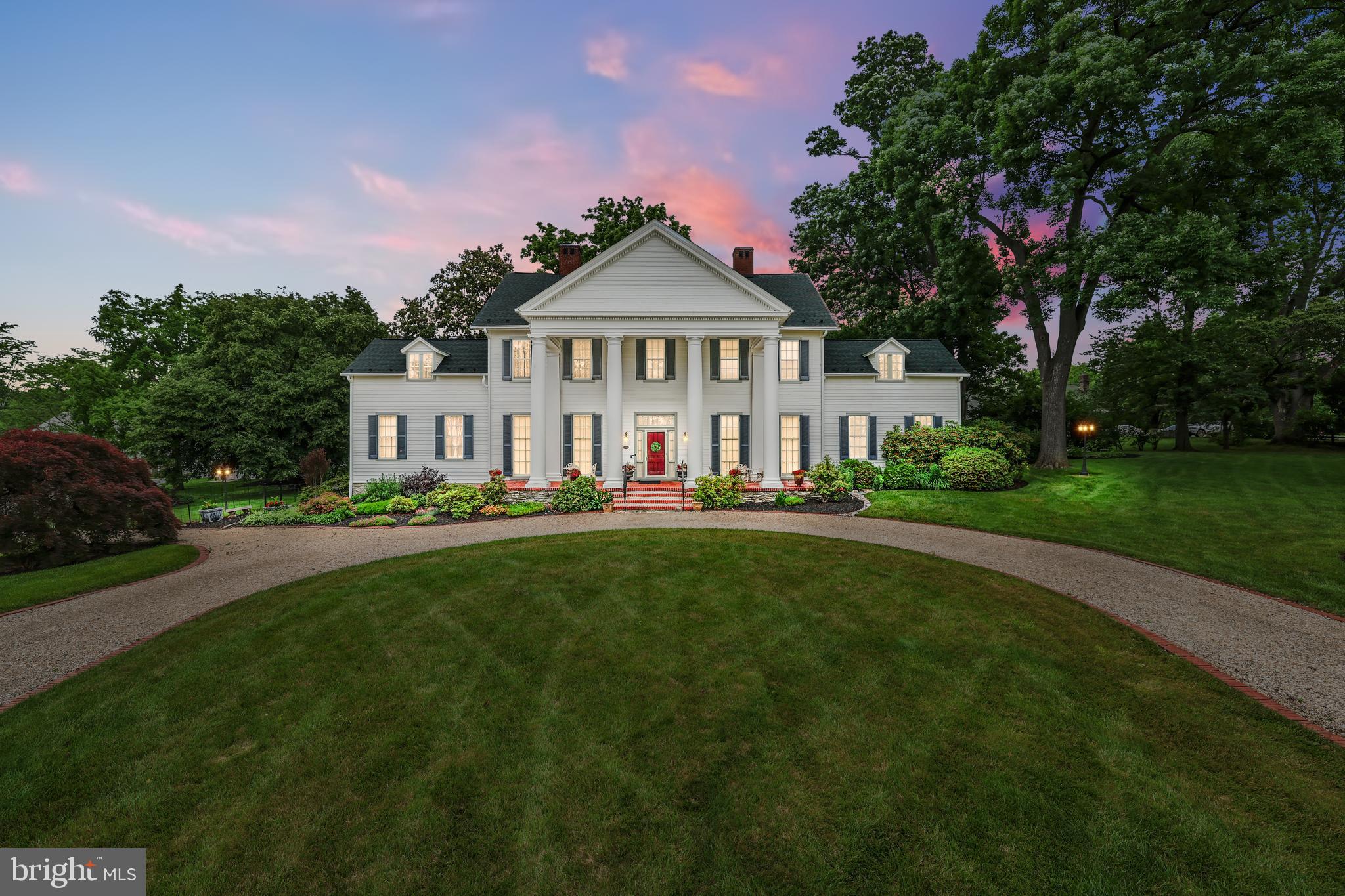 a view of a big house with a big yard and large trees