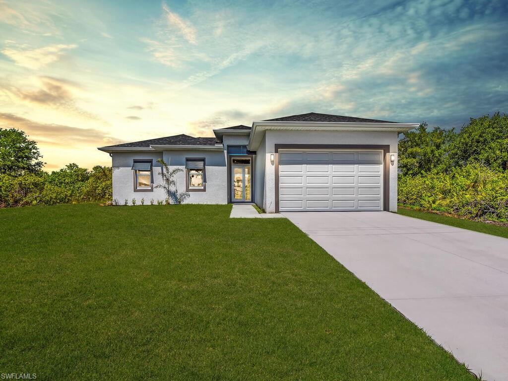 View of front facade featuring a lawn and a garage