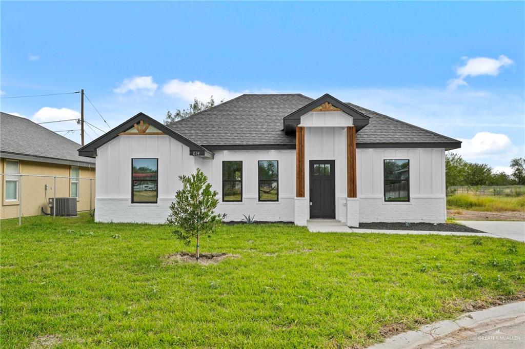 View of front of house with a front yard and central AC