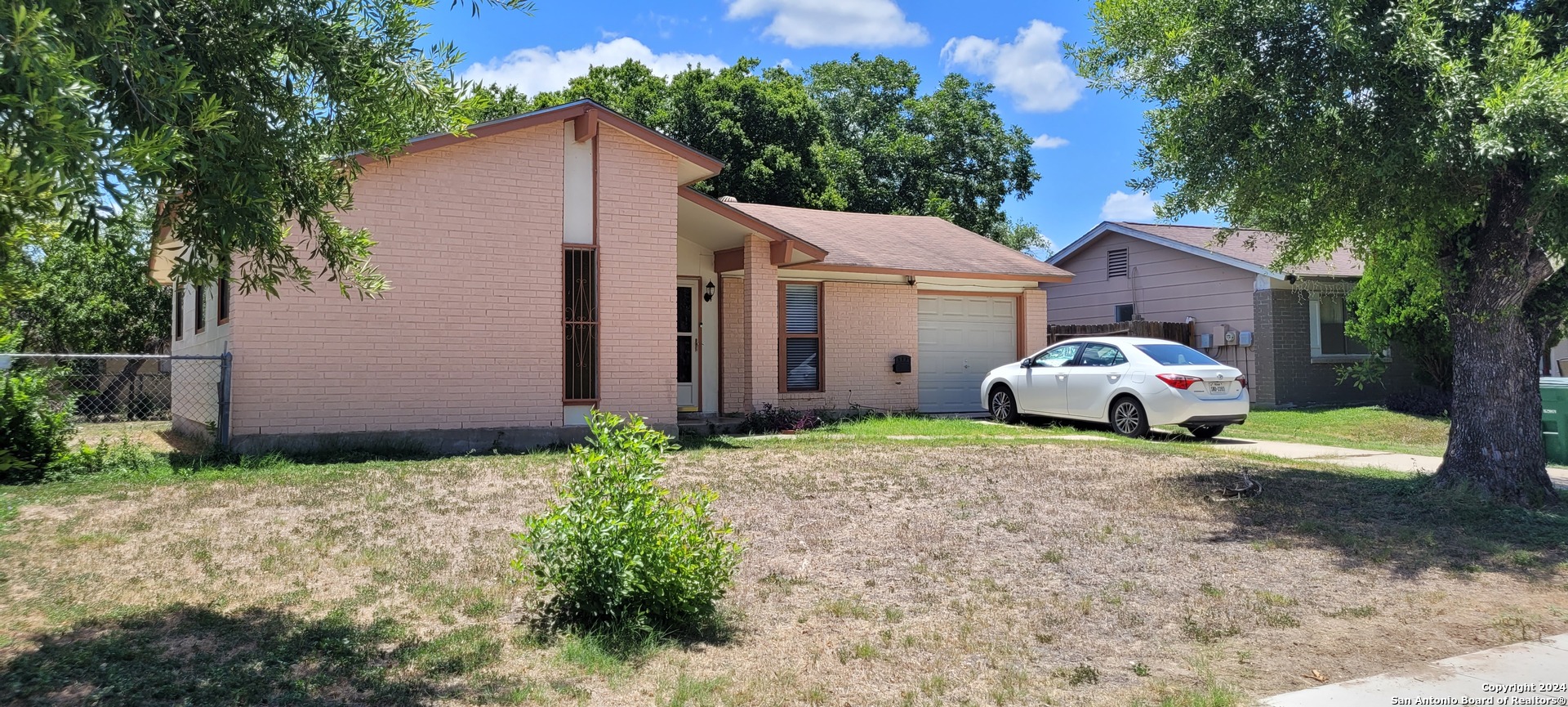 a view of a house with a yard and large trees