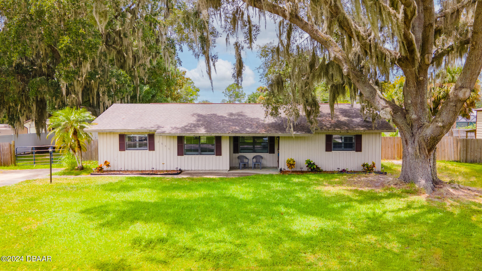 a view of a house with a big yard plants and large trees