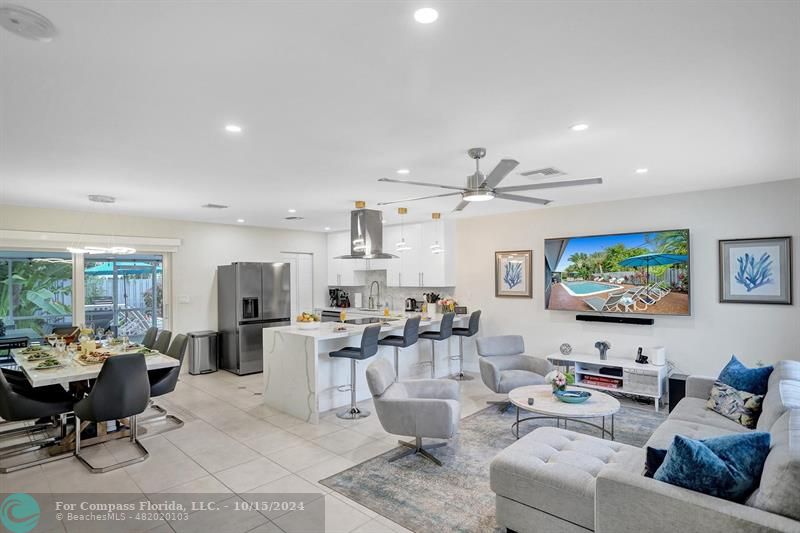 a living room with furniture kitchen view and a flat screen tv