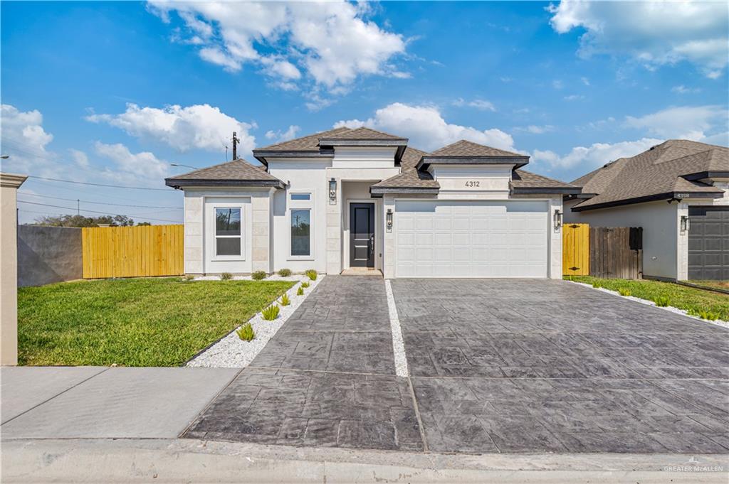 View of front of property with a garage and a front lawn