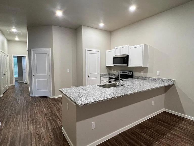 a living room with stainless steel appliances kitchen island granite countertop furniture and a wooden floor